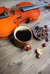 Elegant breakfast still life with violin, cup of coffee, gooseberry and walnut jam on wooden background