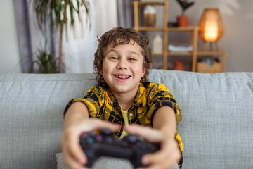 Close up portrait of emotional little boy playing video games on gamepad, pushing buttons on joystick © Prostock-studio