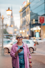 Young plus size woman using smartphone while walking in the city.