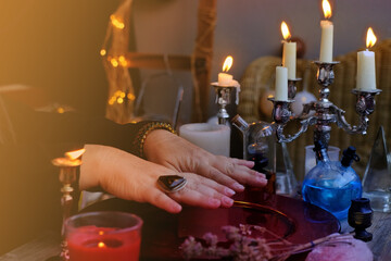 female hands close-up, session of magic in dark room of fortuneteller, magic items on table,...