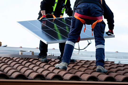 Pareja de t&eacute;cnicos instalando placas solares en una vivienda.	2