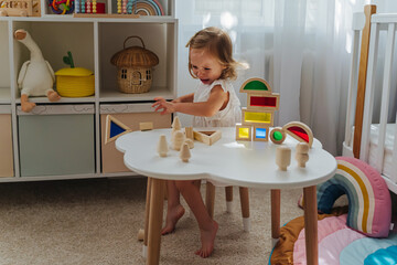 A little girl cries and is naughty sitting at the table in the nursery. Children's tantrums, tears...
