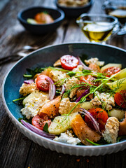 Salmon salad - smoked salmon, white smoked cheese and fresh vegetables on wooden table
