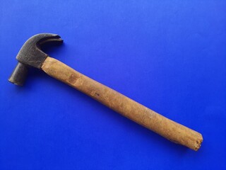 Hammer with wooden handle, isolated on a blue background, space for text.