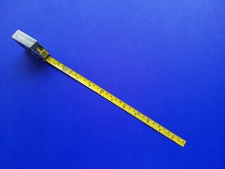 Metal measuring tape, on a blue background, top view with space for text.