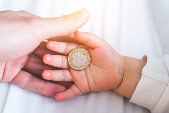 Inflation and financial security concept: Close up of newborn baby holding a euro coin