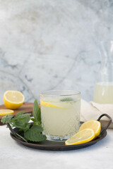A glass of lemonade with lemon on a gray background.