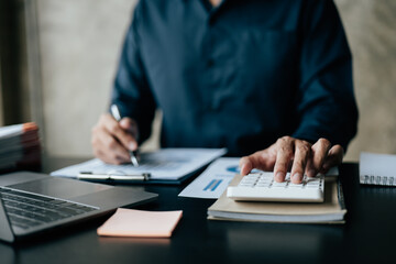 Close up of business hands working and calculating on financial and accounting graft and chart in office space.