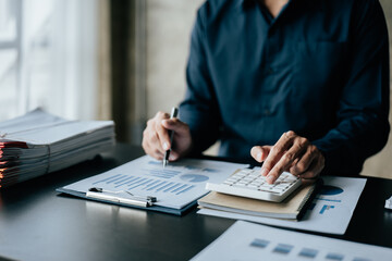 Close up of business hands working and calculating on financial and accounting graft and chart in office space.