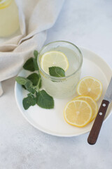 A glass of lemonade with lemon on a gray background.