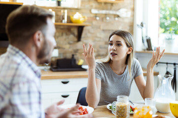 Frustrated young woman arguing with her husband at dining table
