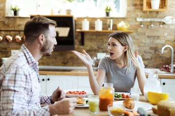 Frustrated young woman arguing with her husband at dining table