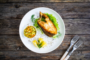 Fish dish - fried halibut with French fries and lemon on wooden table
