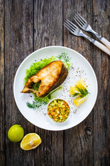 Fish dish - fried halibut with French fries and lemon on wooden table
