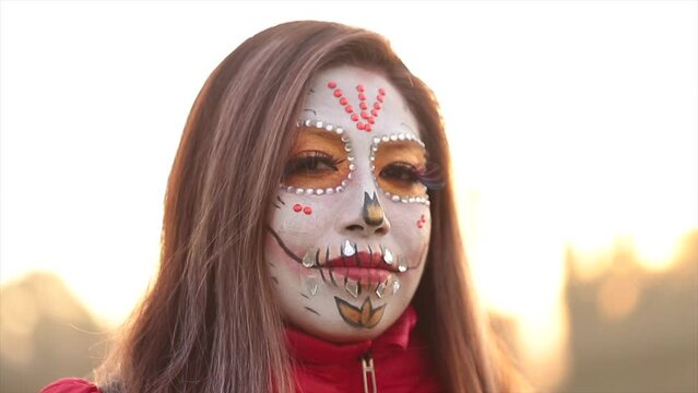 mexican woman with catrina makeup in close up looking at camera for day of the dead celebration