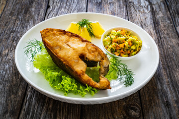 Fish dish - fried halibut with French fries and lemon on wooden table
