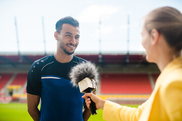 Reporter interviewing football player in a stadium holding microphone in hand