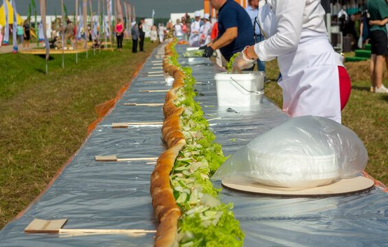 Cooking A Very Large Sandwich With Different Fillings On A Holiday At A Long Table. A Treat For Everyone.