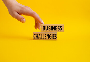 Business challenges symbol. Concept word Business challenges on wooden blocks. Beautiful yellow background. Businessman hand. Business and Business challenges concept. Copy space