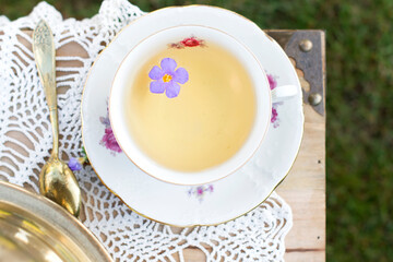 porcelain cup with tea and flower floats in tea, vintage still life, top view