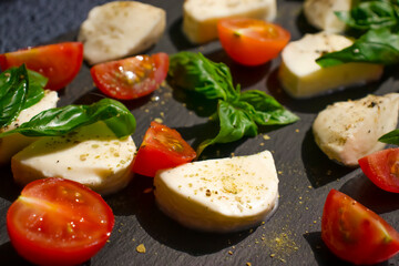 Mozzarella cheese, tomato, basil on a dark background