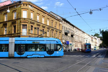 modern blue tram side perspective view in Zagreb, Croatia. major street in downtown. old classic residential buildings and stucco facades in the background. travel and tourism concept. urban scene. - obrazy, fototapety, plakaty