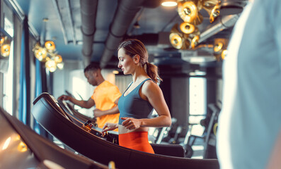 Men and woman, diversity group, in the gym exercising by running on treadmill