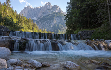 Fototapeta na wymiar cascade on the river Pišnica with the Julian Alps in the backgro
