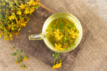 St. John's wort tea is a therapeutic healthy drink A cup on a wooden background A bouquet of St. John's wort on the table The concept of medicinal herbs, phytotherapy Top view