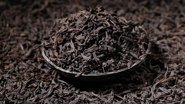 Dried black tea leaves in a bowl. close up. Macro.  view on turntable