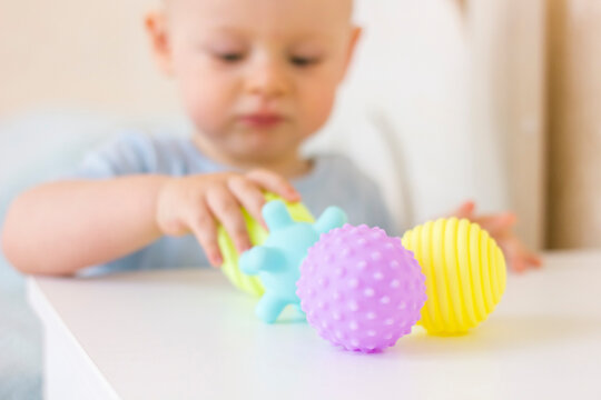 Cute baby boy toddler playing with massage ball.
