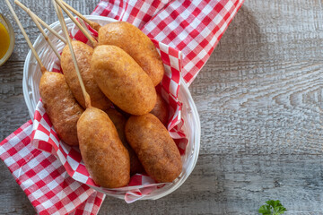 Traditional American street food corn dogs with mustard and ketchup on wooden table