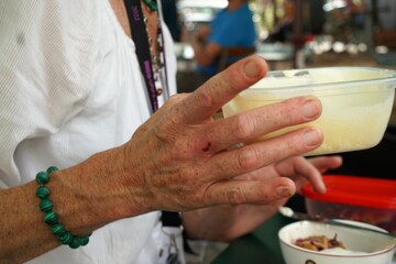 Frauenhand hält Plastikdose mit geschlagener Sahne in Restaurant am Nachmittag im Sommer
