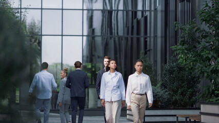 Corporate people walking downtown district on sunny day. Finance company workers