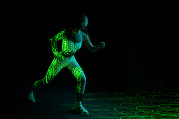Woman in futuristic costume. Female posing in glasses of virtual reality. Augmented reality game, future technology, AI concept. VR. Neon green light.