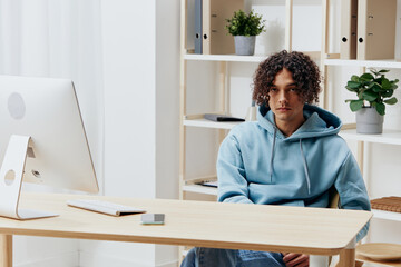 portrait of a man in a blue jacket in front of a computer with phone interior