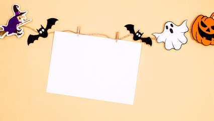 Creative paper card copy space hanged on rope with scary stickers for Halloween on beige  background. Flat lay