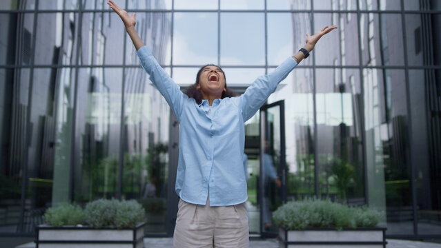 Winning business lady screaming raising hands up in crowded office city center.