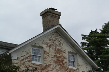 white washed brick building with chimney and two windows
