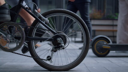 Male legs riding bicycle in black shoes at downtown close up. Rear wheel view.