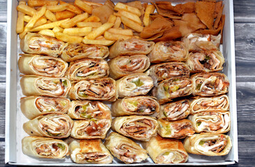 Syrian recipe cuisine background, a box full of pieces of chicken shawerma or shawarma tortilla wrap with onion, tomato, lettuce and garlic sauce in Syrian bread with side french fries and fried bread - obrazy, fototapety, plakaty