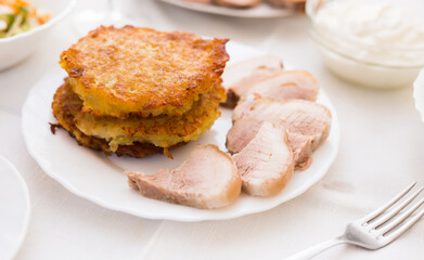 Fried grated potato pancakes with meat on white plate