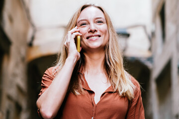 attractive young blonde woman smiling while talking by phone in the street.