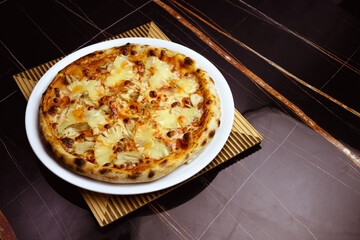 High angle view of delicious hawaiian pizza on black marble 