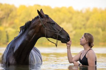 Junge Frau mit Pferd im See