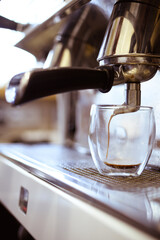 Close up view of coffee pouring in glass from machine in coffee shop 