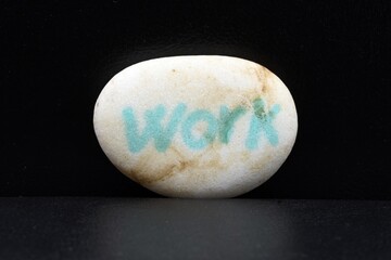 Detalle de una piedra blanca  con la palabra escrita, work, sobre fondo negro