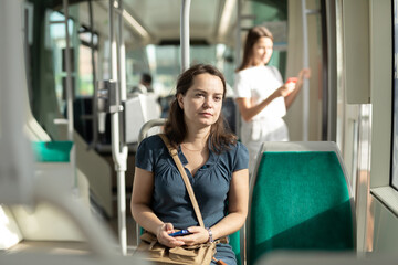 Portrait of positive woman traveling by modern city bus on in sunny day..