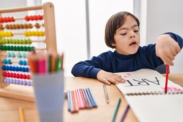 Down syndrome kid drawing on notebook at school
