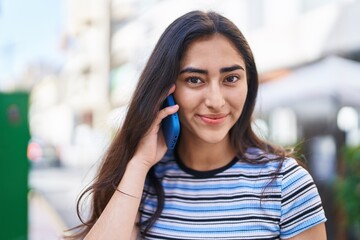 Young hispanic girl smiling confident talking on the smartphone at street